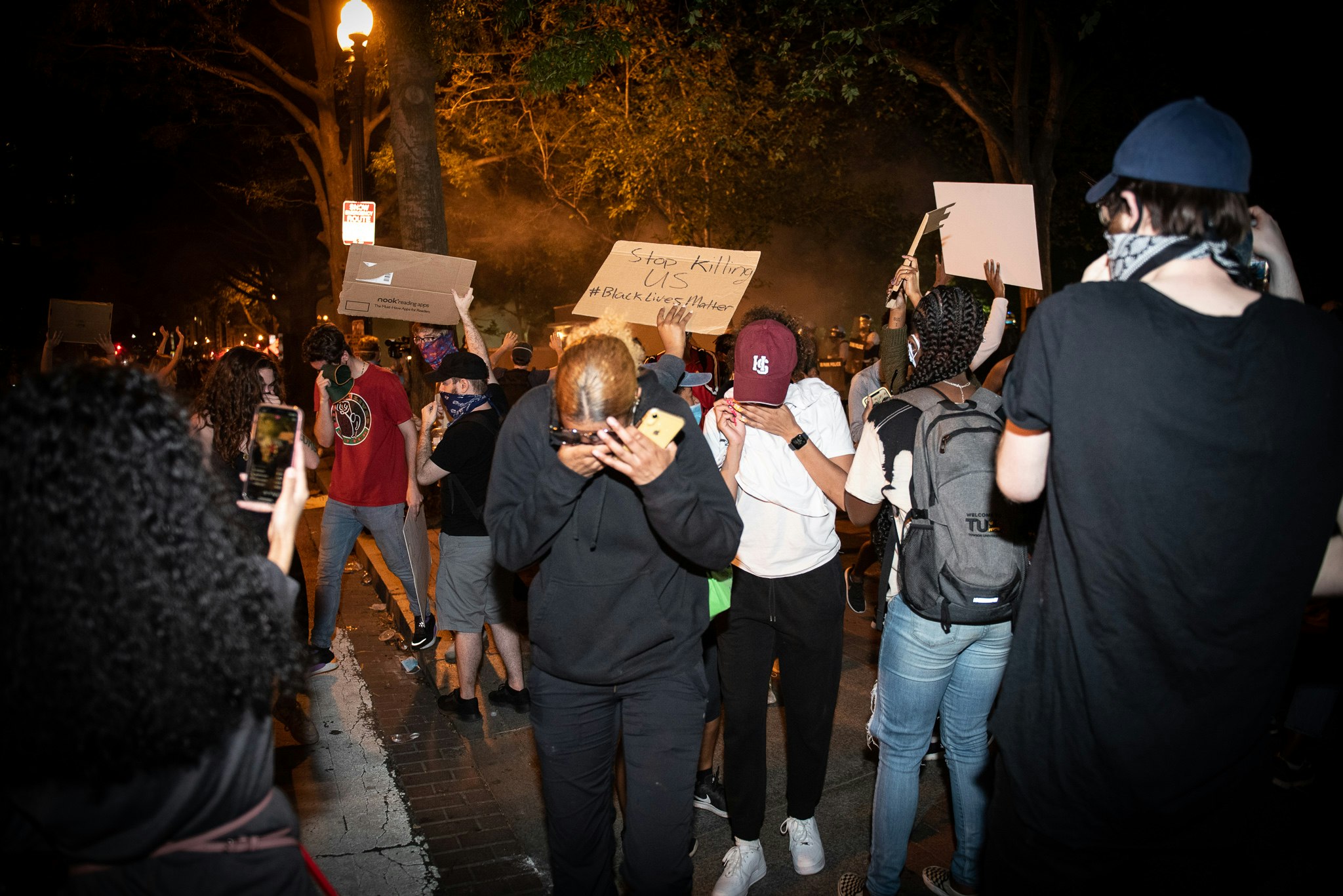 Protestors shield their faces after being exposed to tear gas at a George Floyd protest in Washington DC, 2020