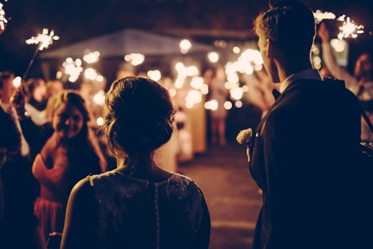 a wedding photo taken from behind the bride and groom looking at the crowd