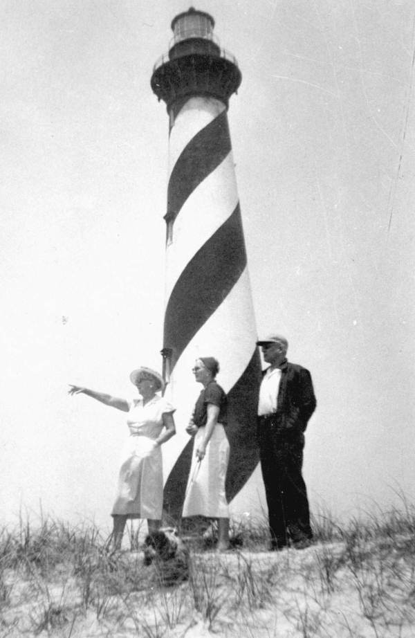 Marjory Stoneman Douglas standing in front of a black-and-white striped lighthouse. She is pointing at something off camera left.
