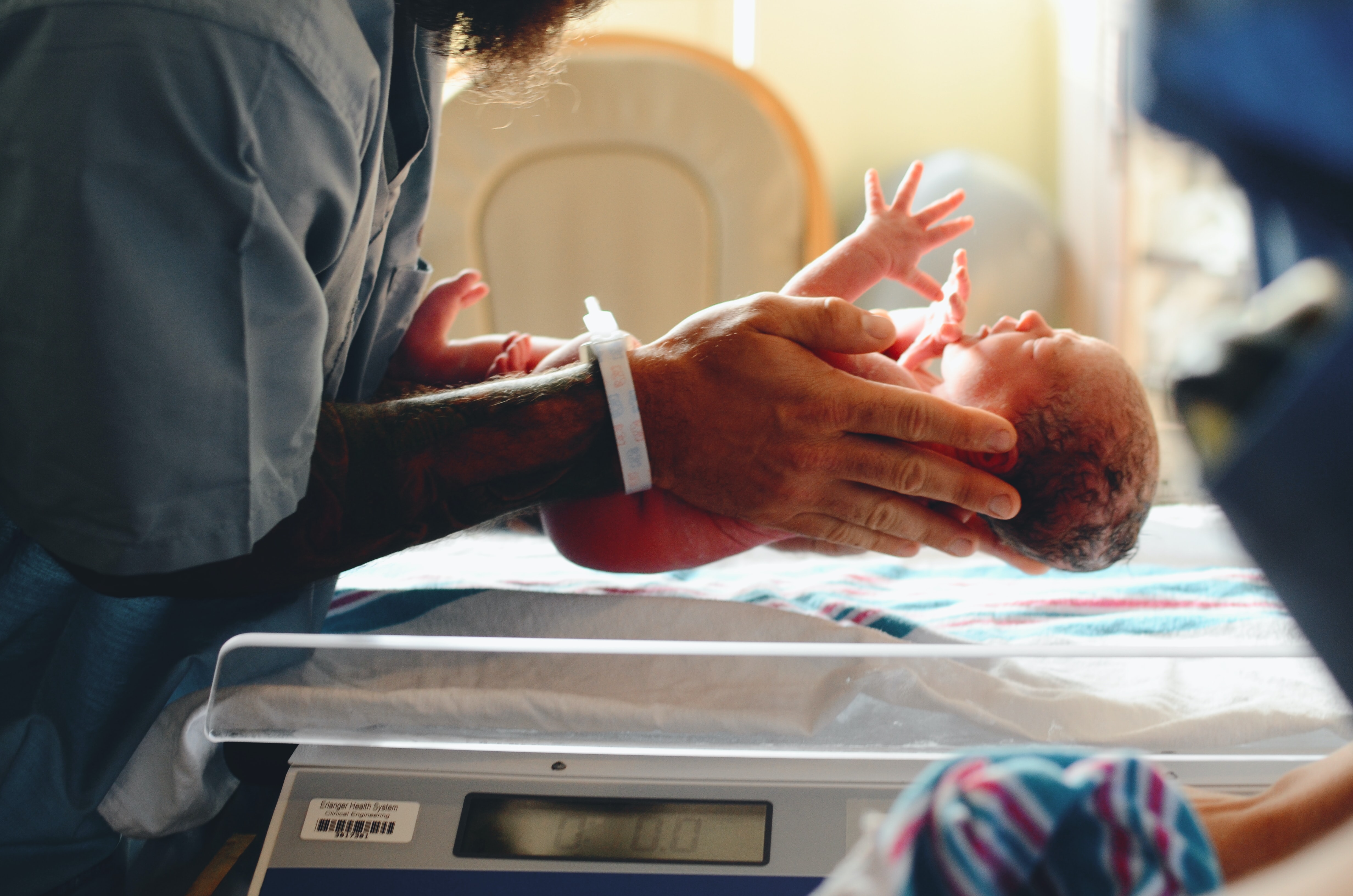 A newborn baby being held by a person wearing scrubs in a hospital setting 