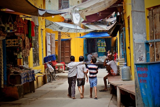 Three children walk through a city marketplace