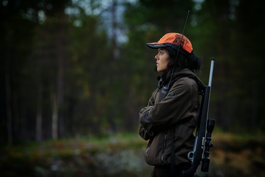 a women wearing a blaze orange cap with a hunting gun