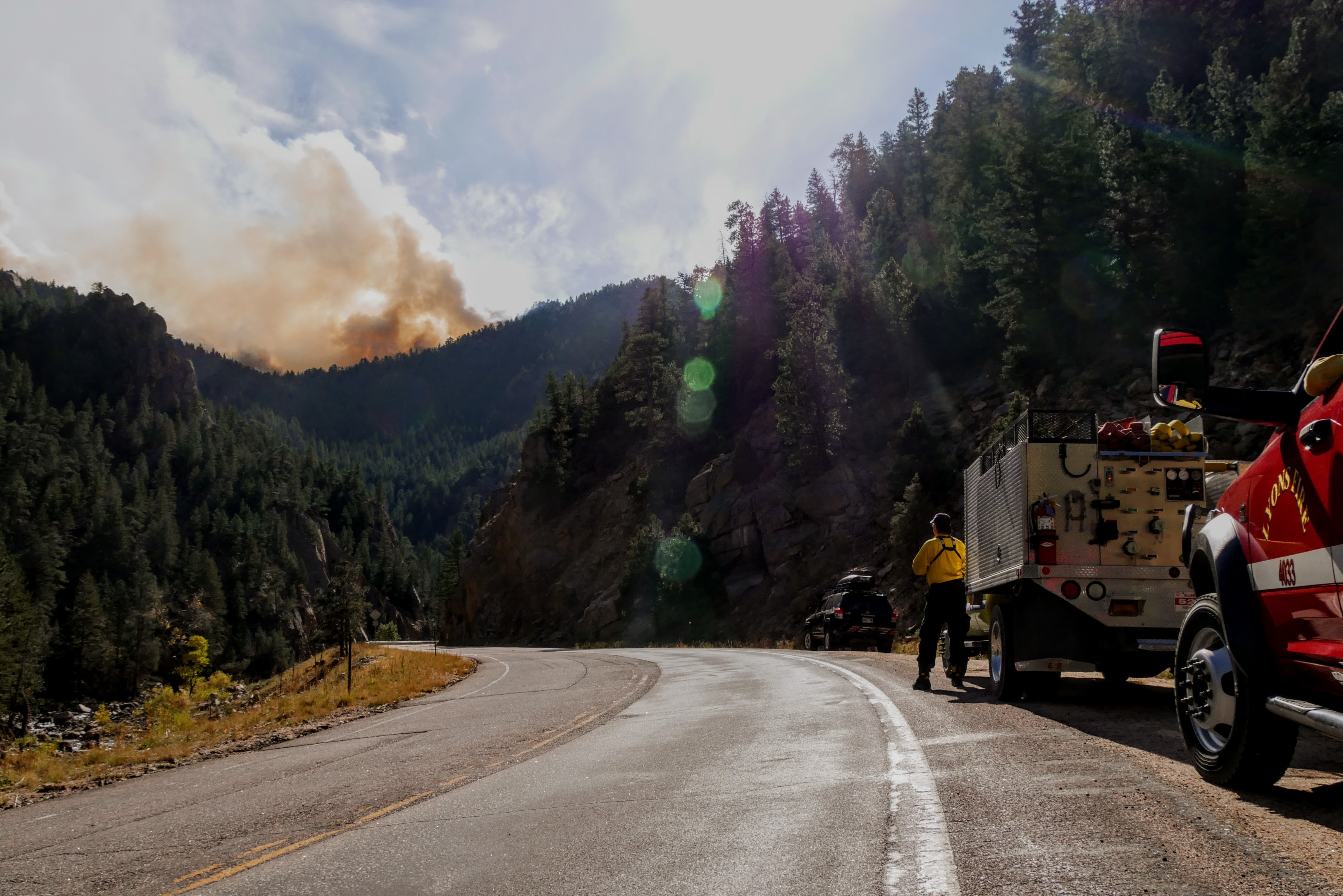 A firefighter looks at the Calwood Fire coming over a ridge, October 2020, Colorado