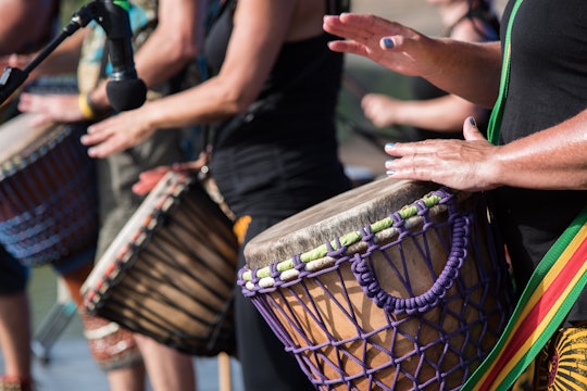 the torsos of people drumming in a line