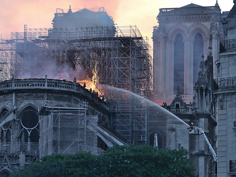 firefighter spraying water on the burned notre dame cathedral