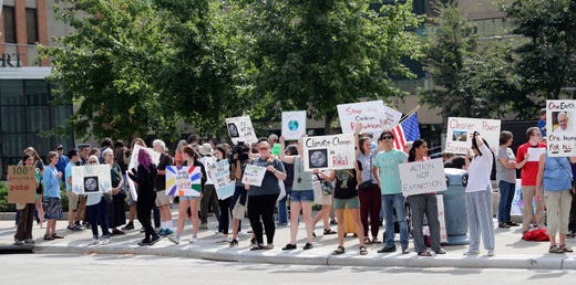 Climate strikers stand on a curb holding signs at Houdini Plaza, in Appleton, Wisconsin