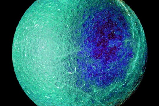 false color image of saturn's moon, rhea. moon is pale green and blue