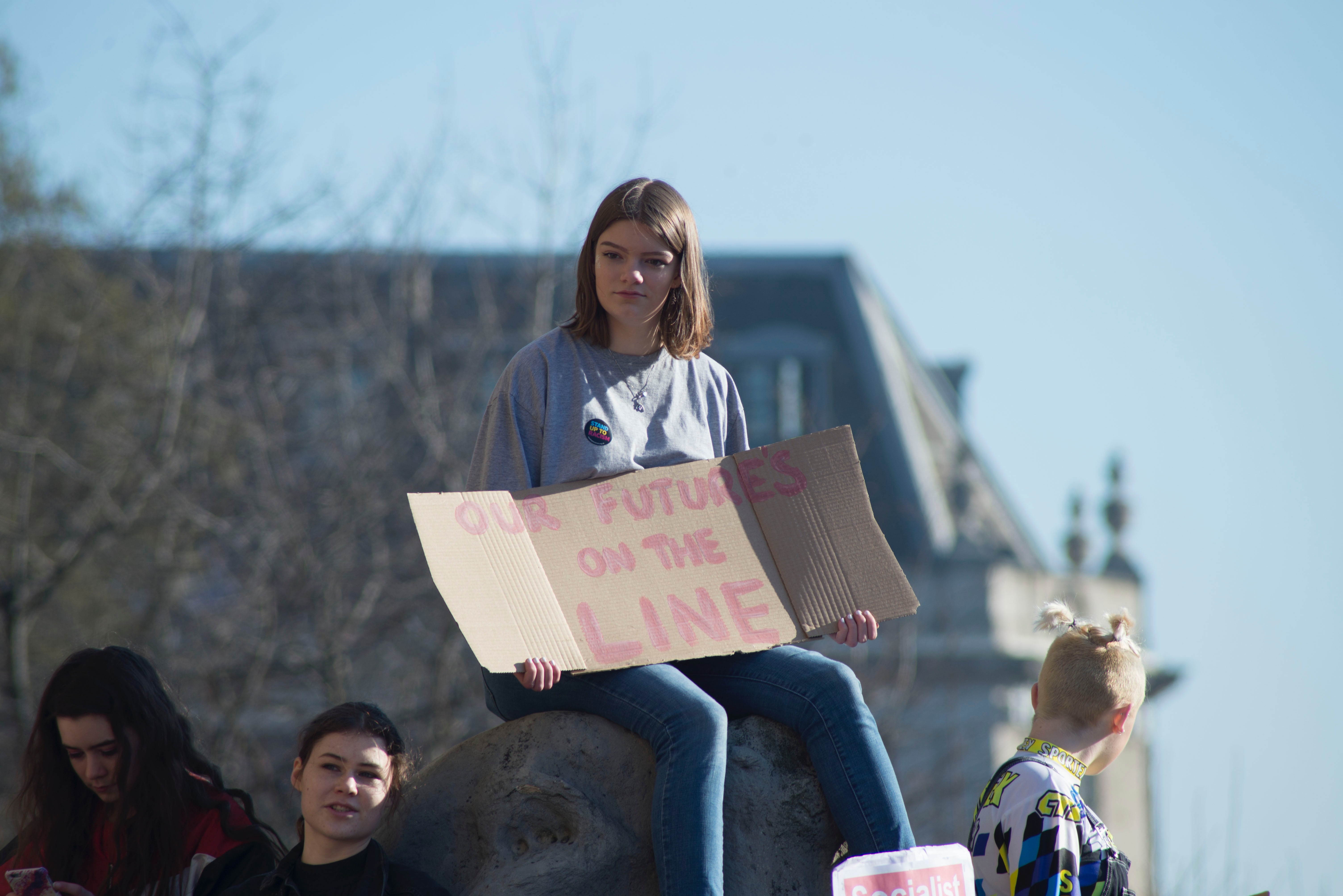 A woman at a climate change protest holds a sign that reads "Our future's on the line."