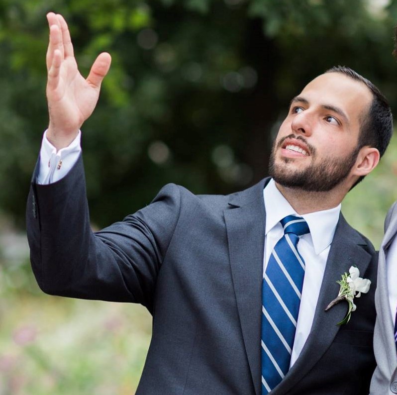 Juan Ruiz in a suit looking up outside