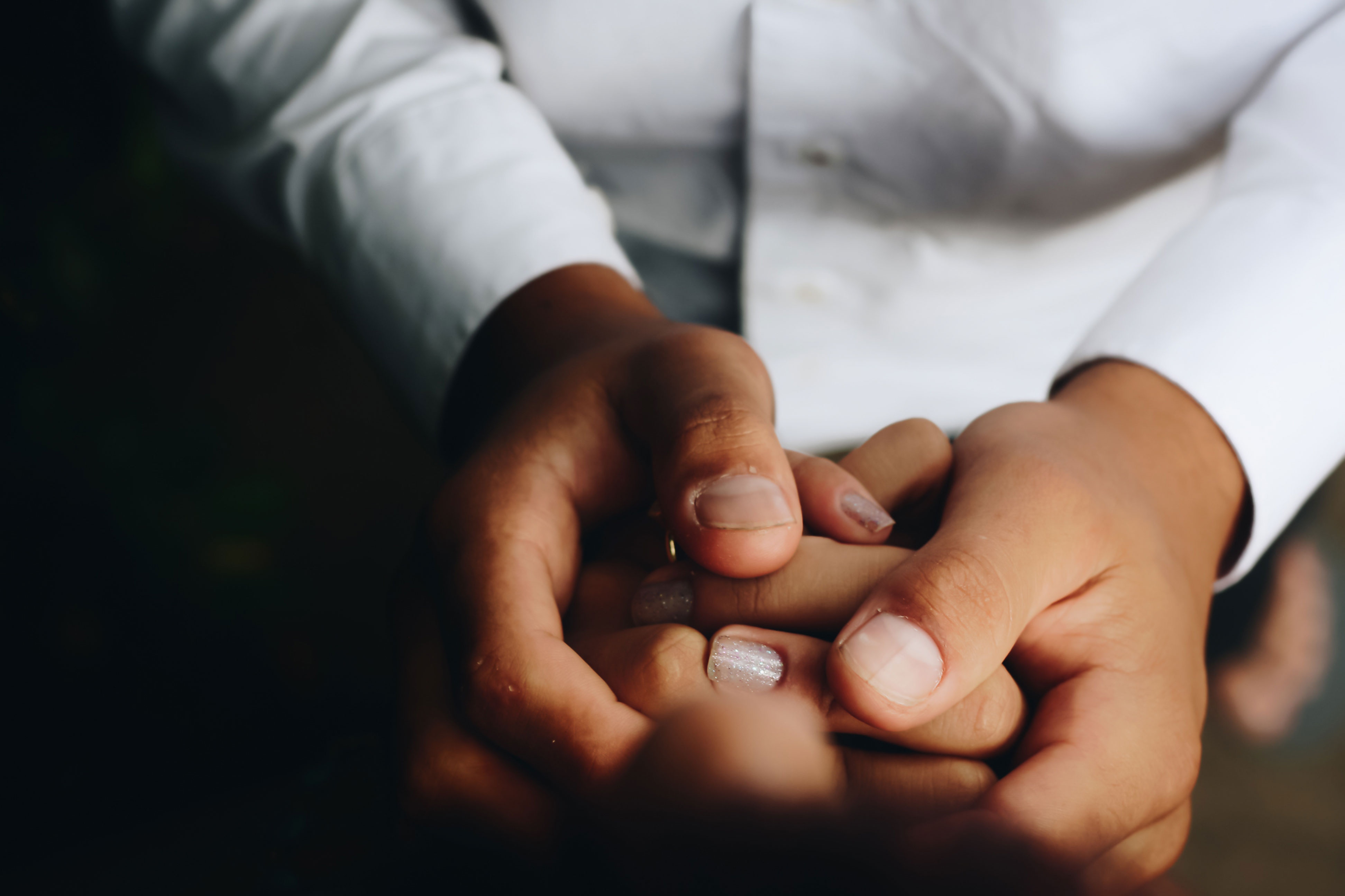 One person holding the hands of another, in a caregiver gesture.