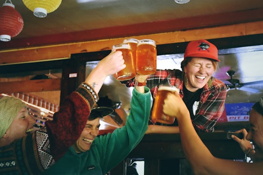 People at a bar clinking tall mugs of beer.