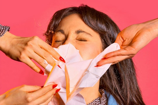 woman sneezing woman sneezing while others put tissues in front of her mouth