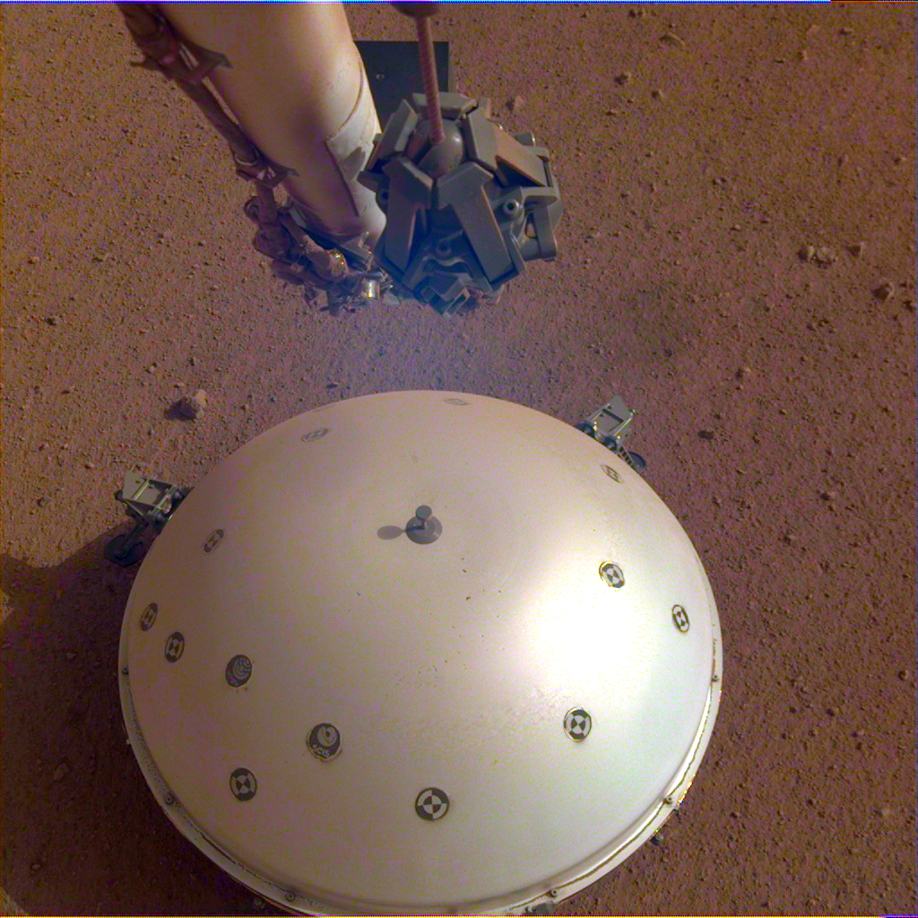 A white dome covers the seismometer from NASA's InSight rover, on the surface of Mars.
