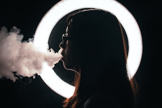 person in profile exhaling smoke