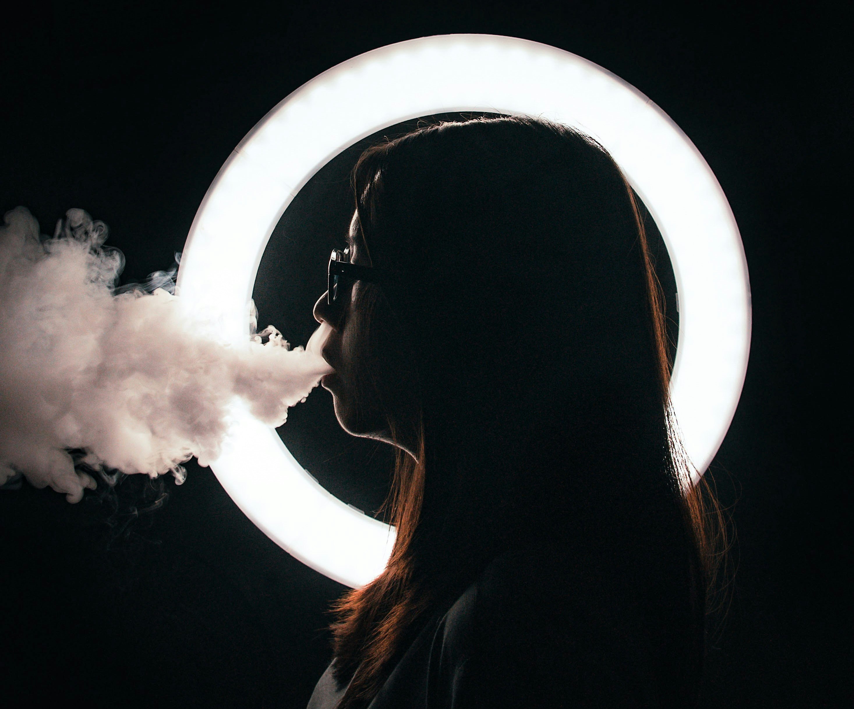 person in profile exhaling smoke
