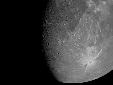 a detailed image of a large moon with round pockmarks on the surface