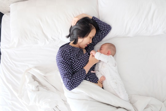 a woman laying in bed face to face with her baby
